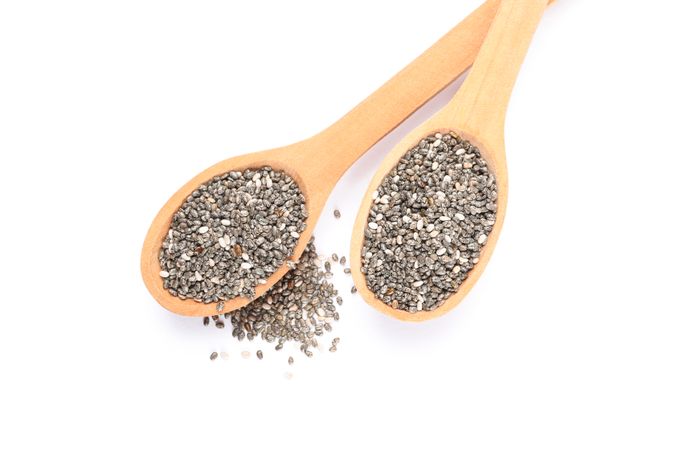 Chia seeds and wooden spoons isolated on blank background