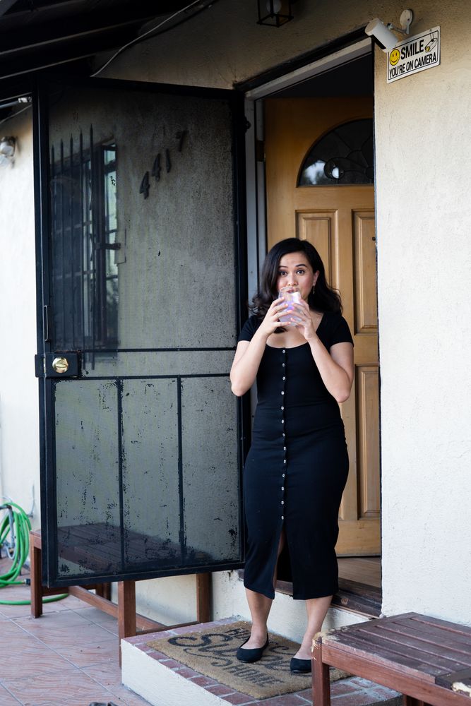Woman smiling and drinking a glass of wine in front of her house