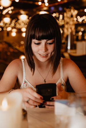 Smiling woman using smartphone in restaurant