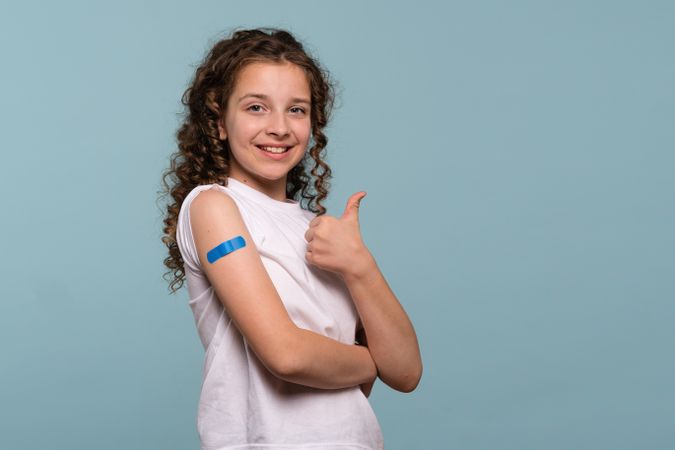 Girl giving a thumbs up after vaccination.