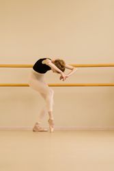Ballet dancer stretching, leaning forward with curved posture.
