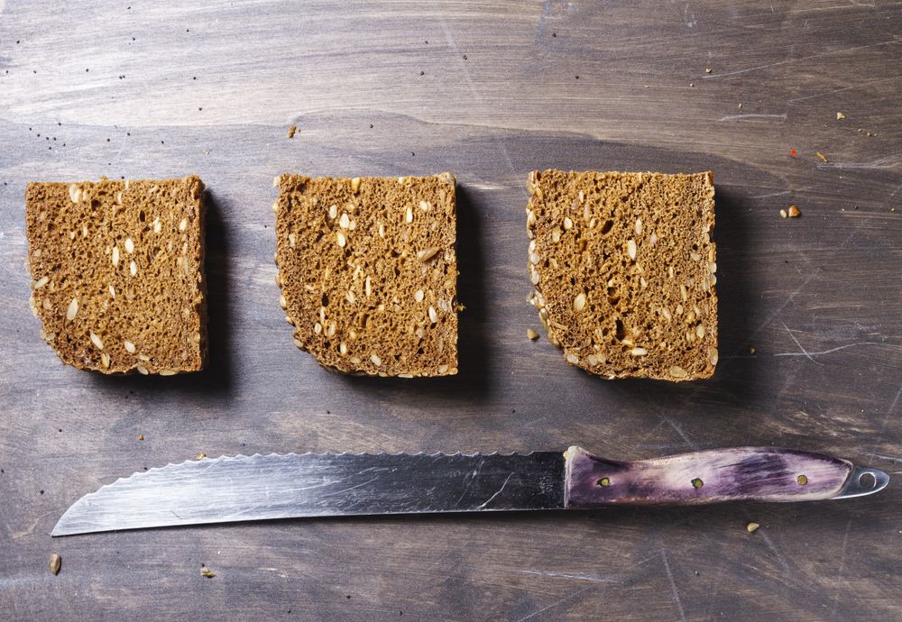 Sliced bread with knife on wooden background