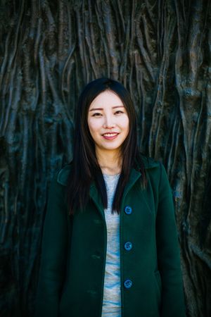 Cheerful Asian woman leaning on rough wall