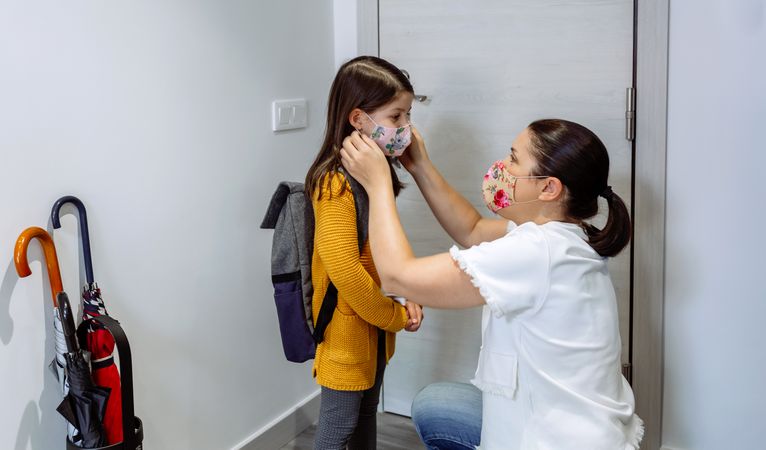 Mother putting the mask on her daughter