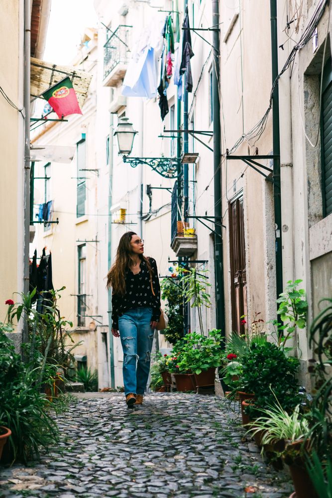 Young casual brunette walking on cobblestone street of old city