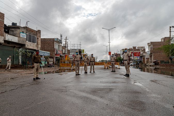Group of policemen wearing facemasks standing in empty neighborhood in India