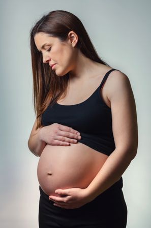 Beautiful pregnant woman looking her belly isolated