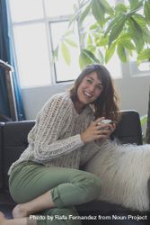 Female laughing on cozy sofa with cup of tea 5qwywb