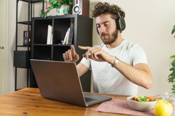 Young man using sign language to communicate on a video call at home.