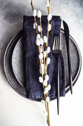 Table setting for Easter dinner with pussy willow on navy napkin