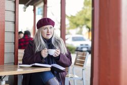 Woman holding a cup while looking thoughtfully into the distance.