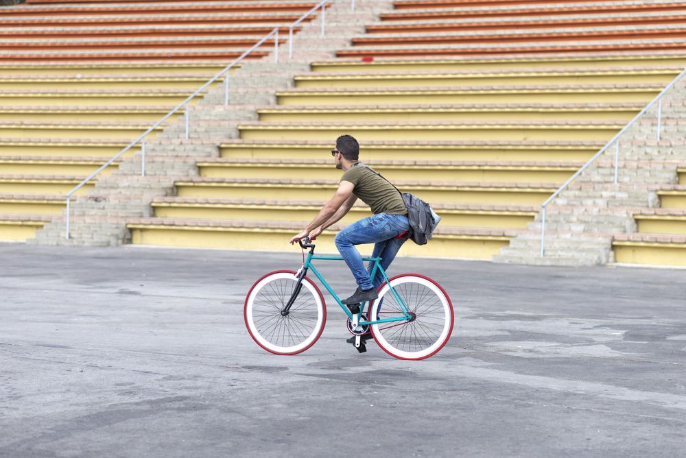 Male on bicycle with yellow outdoor seats in background