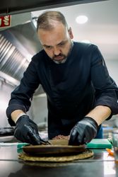 Serious male chef serving plate in kitchen