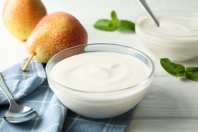 Composition with cream yogurts and fruits on light background, space for text