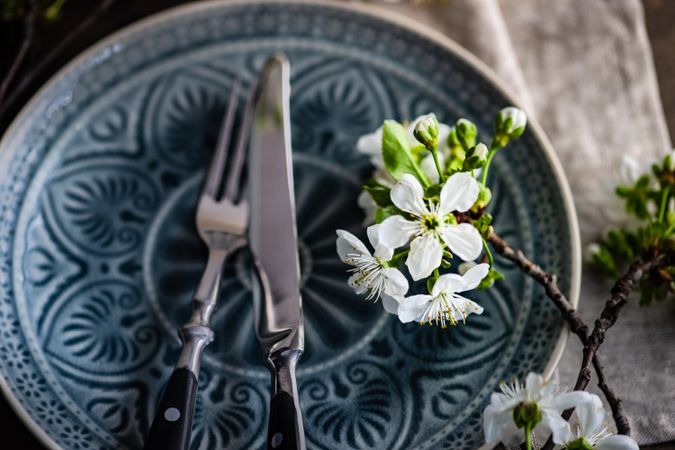 Spring table setting with delicate flower on patterned plate