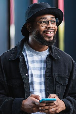 Positive Black hipster man using mobile phone