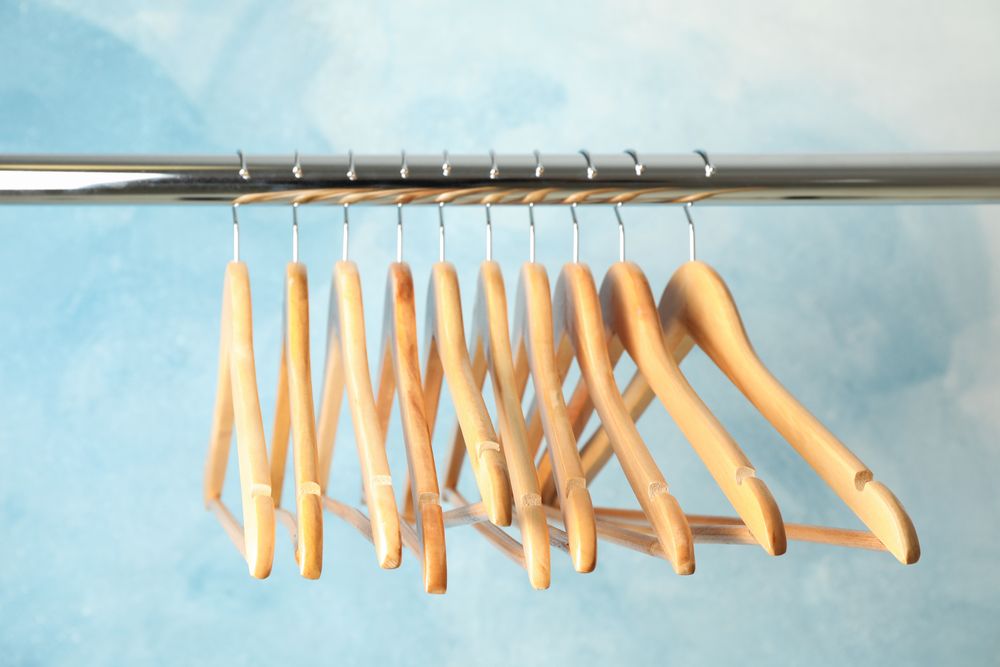 Hangers on rod against blue background, space for text