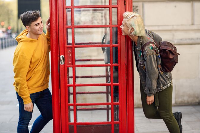 Male and female chatting from different sides of a phone booth