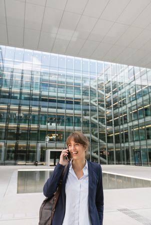 Smiling entrepreneur browsing smartphone outside office building