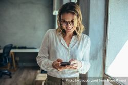 Female entrepreneur looking at her mobile phone and smiling 5p3WO0