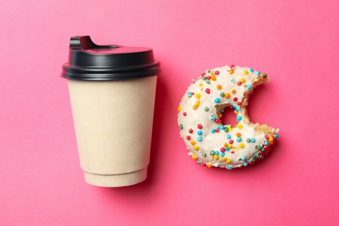 Paper cup and donut on pink background