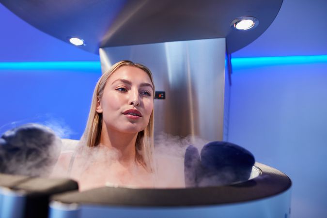 Blonde woman in cryotherapy chamber looking out over the top