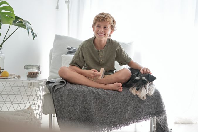 Smiling boy stroking purebred dog lying nearby