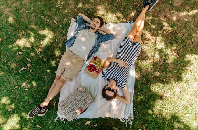 Couple on picnic lying on blanket in grass outdoors
