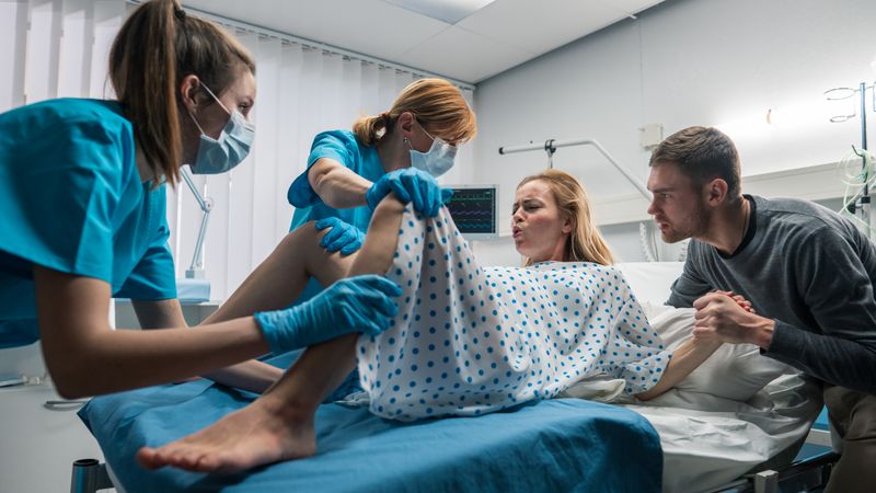 Wide Angle Shot of a Woman in Labor Pushes to Give Birth