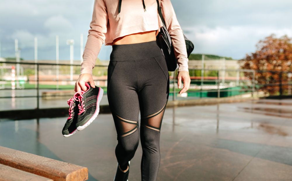 Unrecognizable sportswoman with gym bag and sports shoes walking to go to training