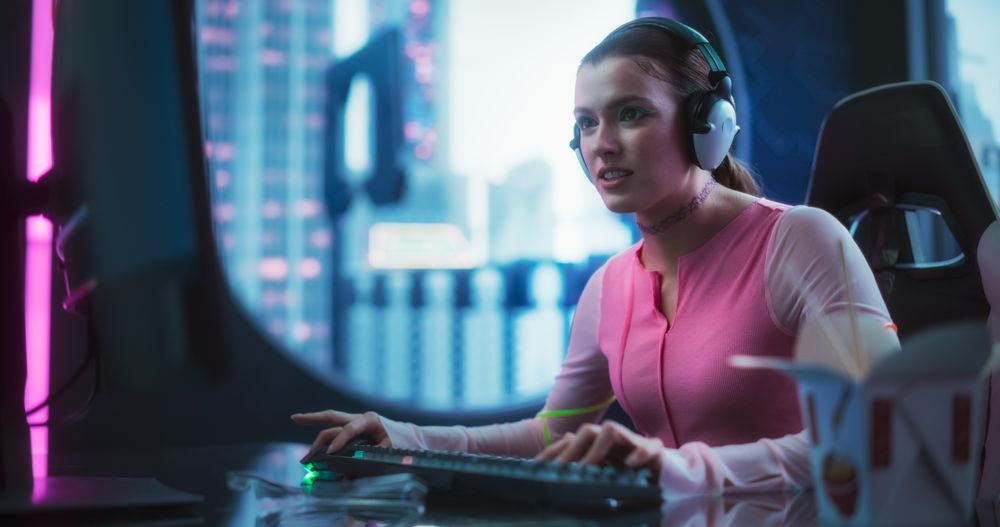 Stylish Young Woman Playing Video Games on a Desktop Computer in a Technologically Advanced Room with Futuristic Cyberpunk City in the Background.