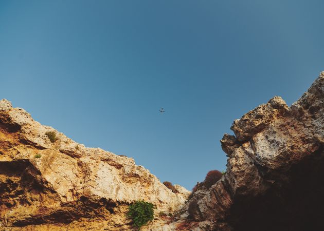 Looking up at blue sky from bottom of rocks