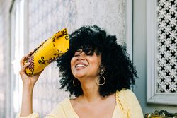Happy Black female with yellow clutch