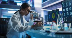 Medical Research And Development Center: Female Asian Scientist Using Microscope To Analyze Petri Dish Sample.