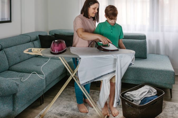 Mother teaching her teen son to iron