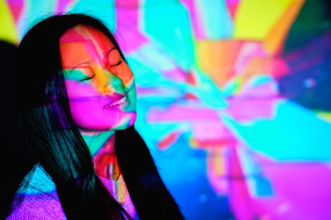 Dreamy Asian woman under colorful neon lights