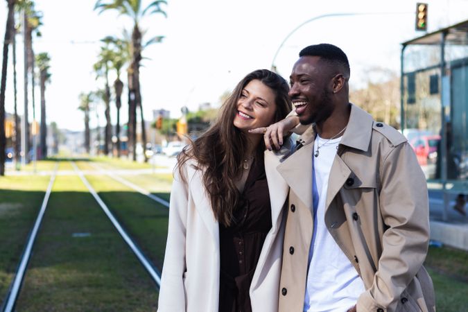 Happy multiethnic couple in stylish clothes walking around the city