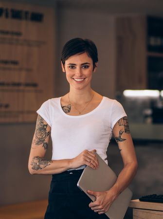 Female with tattoos looking at camera and smiling in a cafe