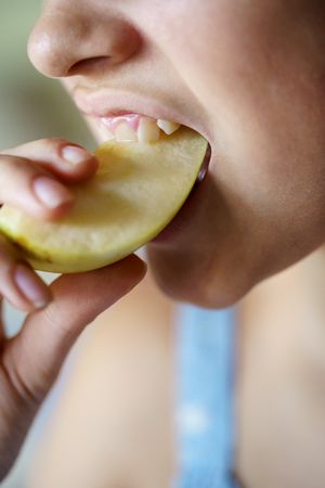 Girl biting into apple slice