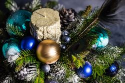 Blue and gold Christmas baubles in pine centerpiece with peacock feathers