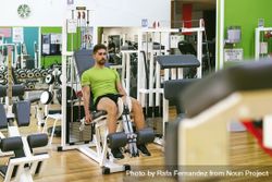 Male in green t-shirt working out legs using gym equipment 4ANxEb