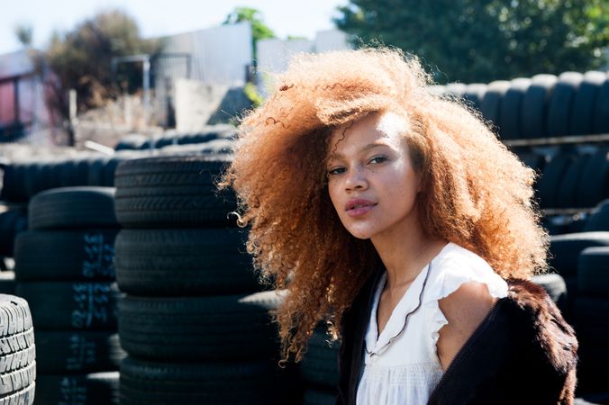 Close up shot of young woman with afro and freckles outside in front of tires