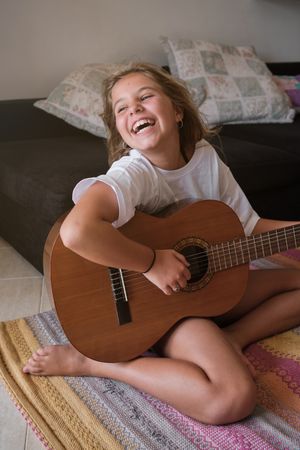Girl with guitar having fun at home