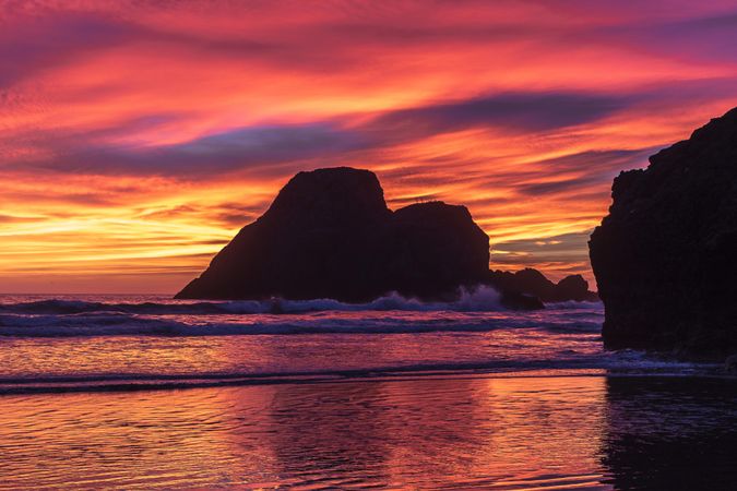 Looking out at scenic view of rocks in the Pacific Ocean during an orangey dusk
