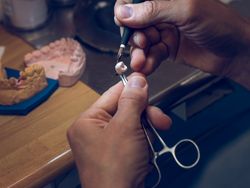 Anonymous dental specialist coloring ceramic tooth