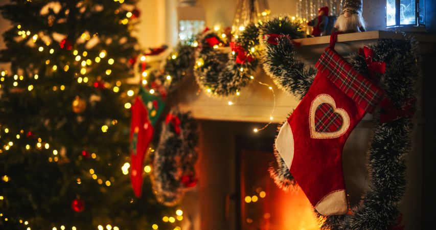 Close Up on Decorated Fireplace with Stockings Next to a Christmas Tree.