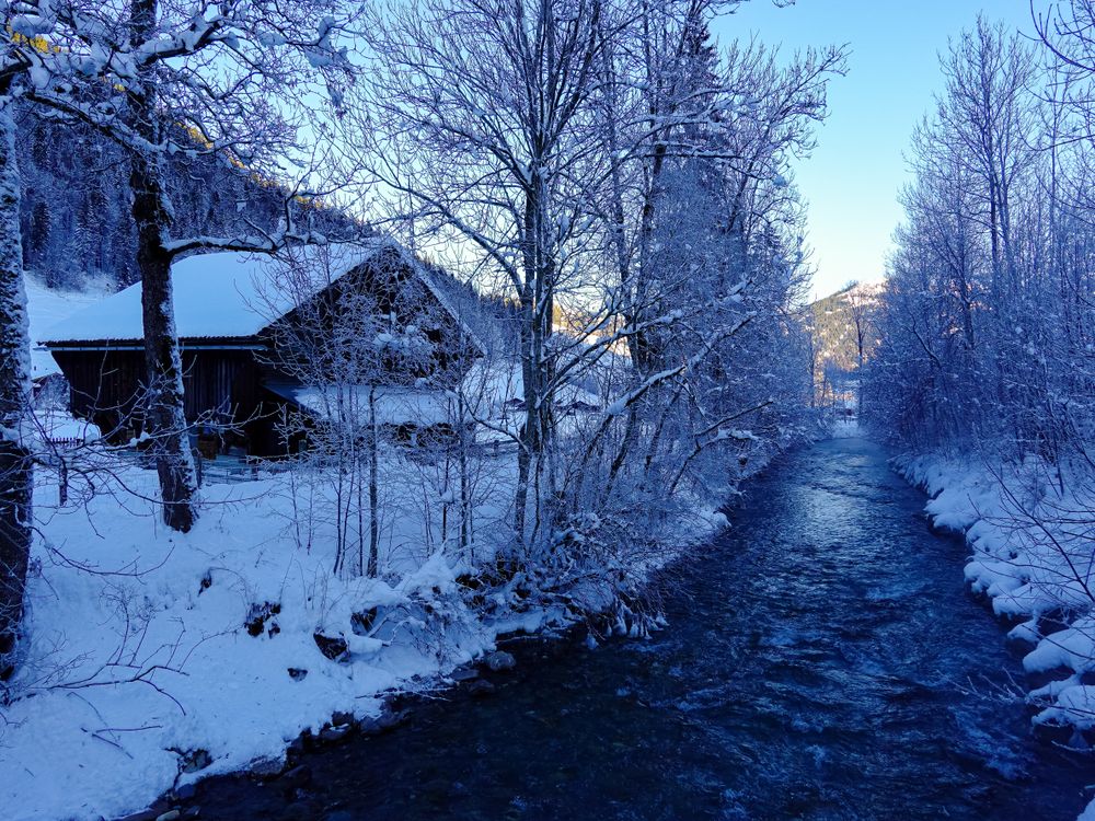 Snow covered barn next to the river La Sarine, Gstaad