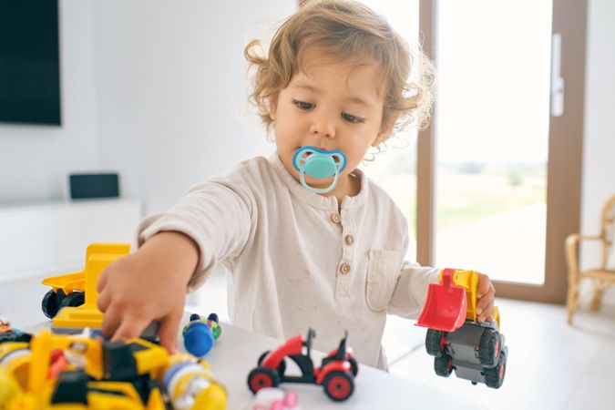 Cute kid playing with toys in light apartment