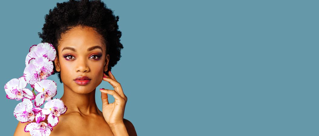 Studio beauty shot of a Black woman with purple flowers