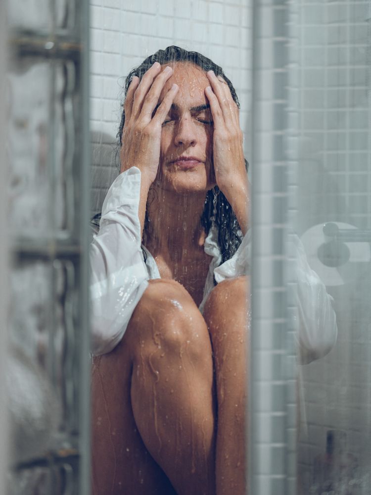Depressed woman sitting in shower